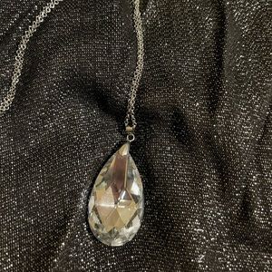 Glamorous, long, silver-tone necklace with sparkling clear pendant.